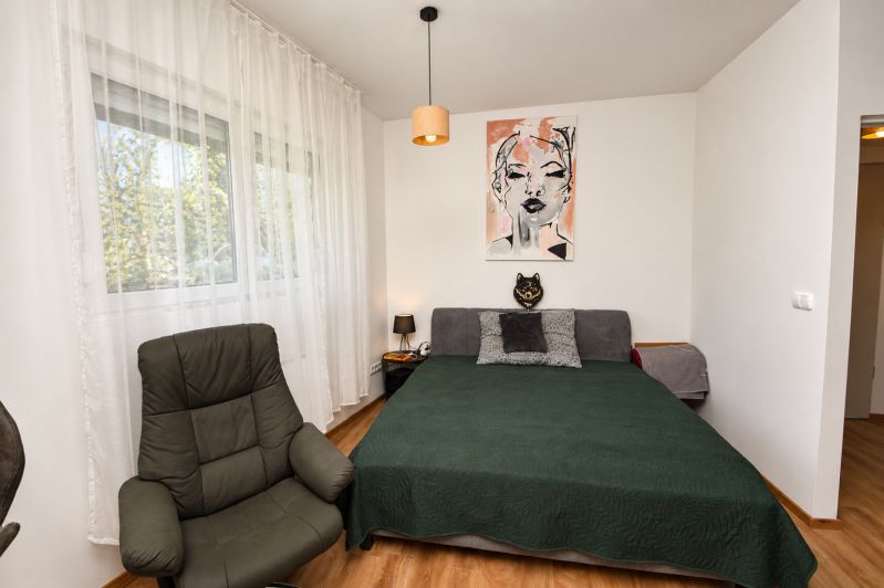 Schlafzimmer in einer Einzimmerwohnung mit Sessel, Bett und Boden in Holzoptik.