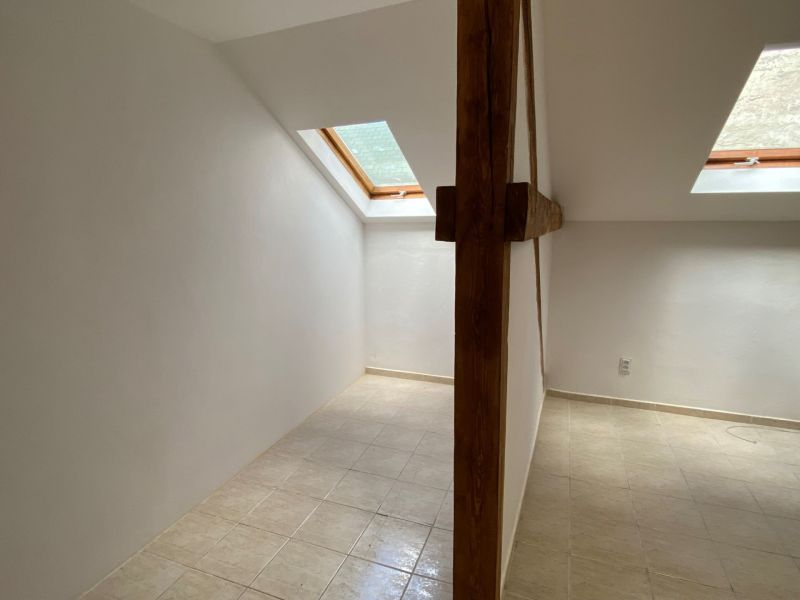 Podkrovný priestor kancelárie s dreveným trámom a strešnými oknami.  
-  
Dachbodenbüro mit Holzbalken und Dachfenstern.