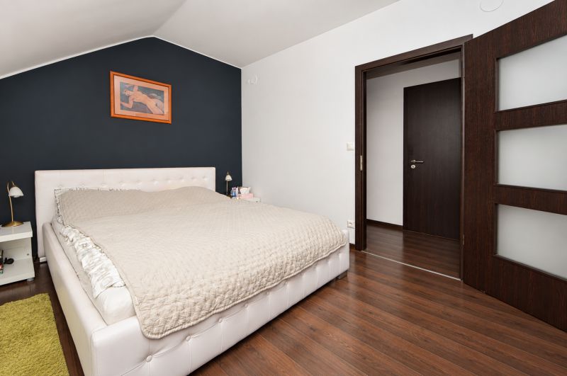 Helles Schlafzimmer mit Bett und Holzboden in einem Einfamilienhaus.