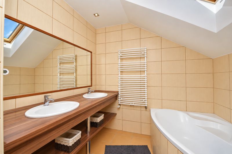 Ein Badezimmer mit Doppelwaschbecken, Spiegel und Badewanne im Dachgeschoss eines Einfamilienhauses.