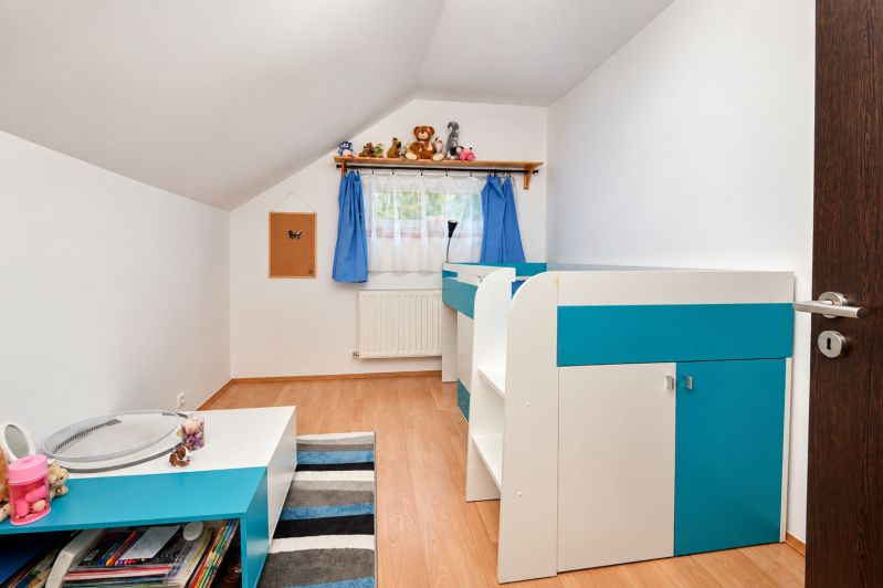 Ein Kinderzimmer in einem Einfamilienhaus mit blauer Dekoration und einem Boden in Holzoptik.
