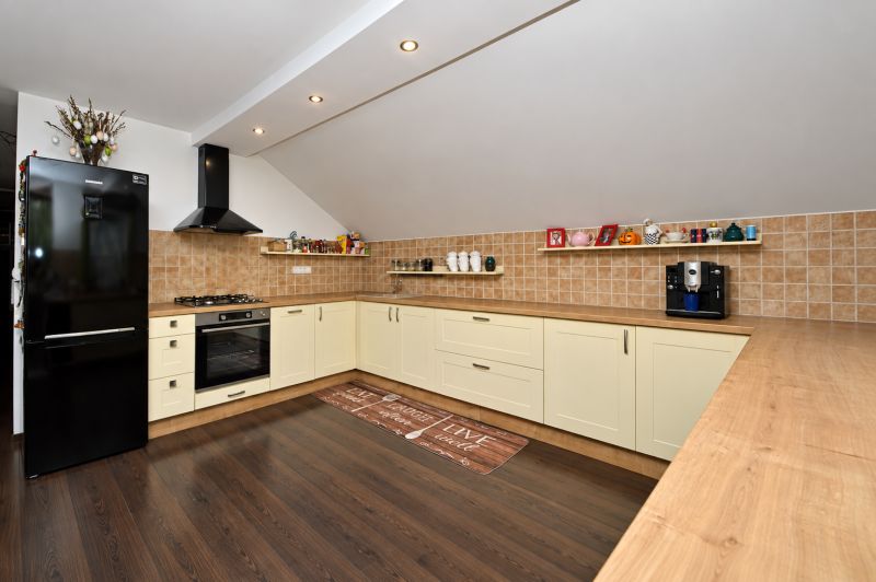 Küche in einem Einfamilienhaus mit Holzboden und cremefarbenen Schränken.