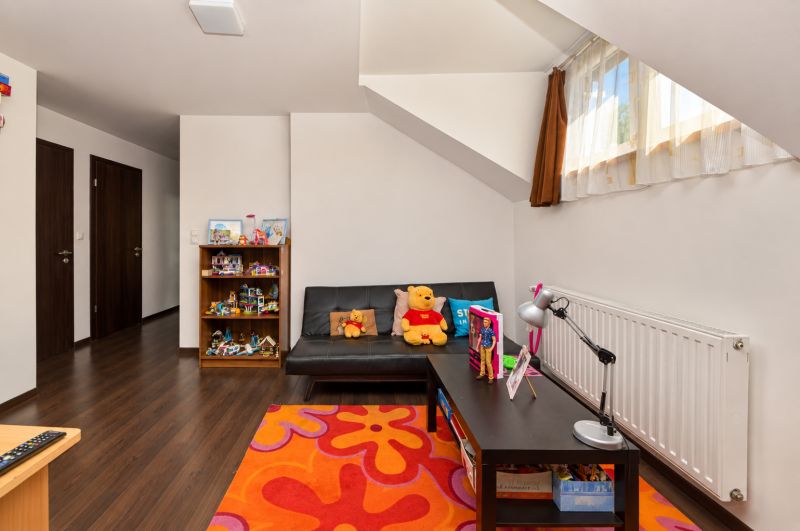 Kinderzimmer mit Holzboden, Spielzeug und Sofa in einem Einfamilienhaus.