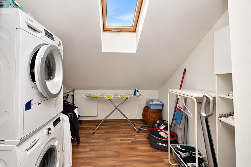 Waschküche im Dachgeschoss eines Einfamilienhauses mit Boden in Holzoptik.