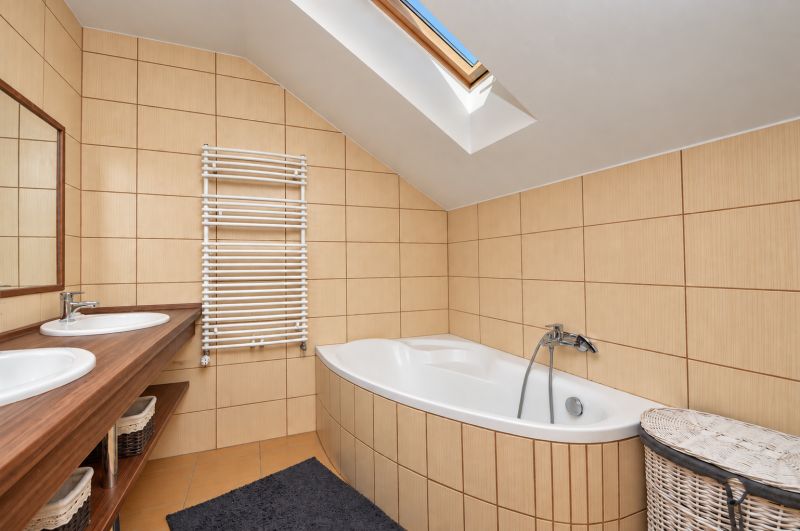 Ein Badezimmer im Dachgeschoss mit Badewanne, Doppelwaschbecken und Dachfenster in einem Einfamilienhaus.
