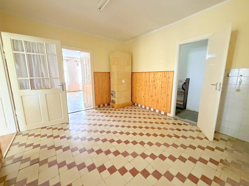 Ein Raum in einem Einfamilienhaus mit Fliesenboden und Holzverkleidung an den Wänden.