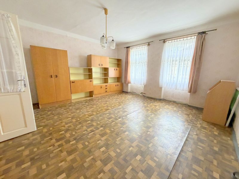 Geräumiges Wohnzimmer in einem Einfamilienhaus mit Einbauschränken und einem Boden in Holzoptik.