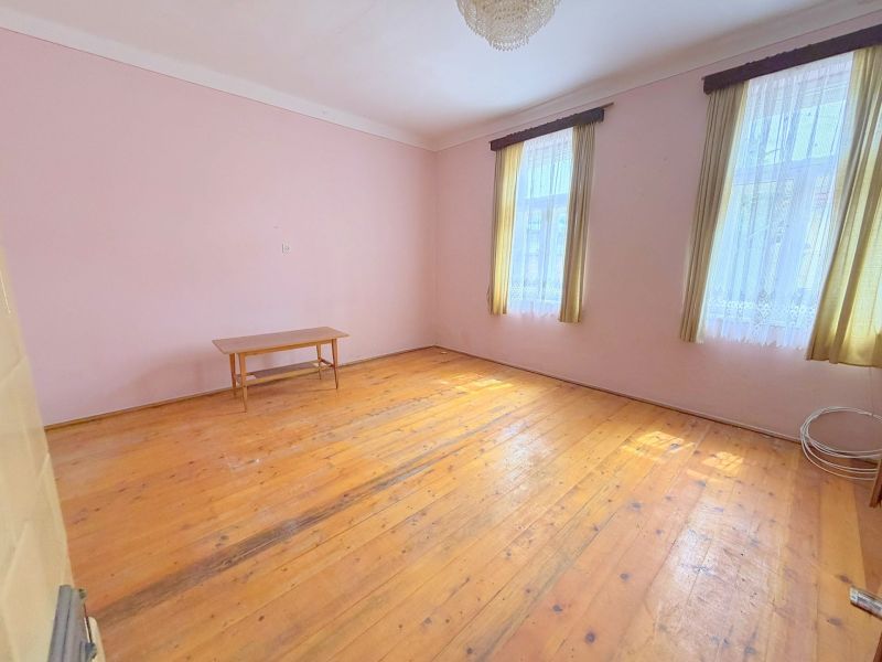 Ein Raum eines Einfamilienhauses mit einem Holzboden, einem Tisch und Vorhängen.