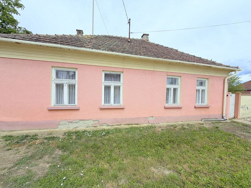 Ein Einfamilienhaus in Dunakiliti mit rosa Fassade und vier Fenstern im Erdgeschoss.