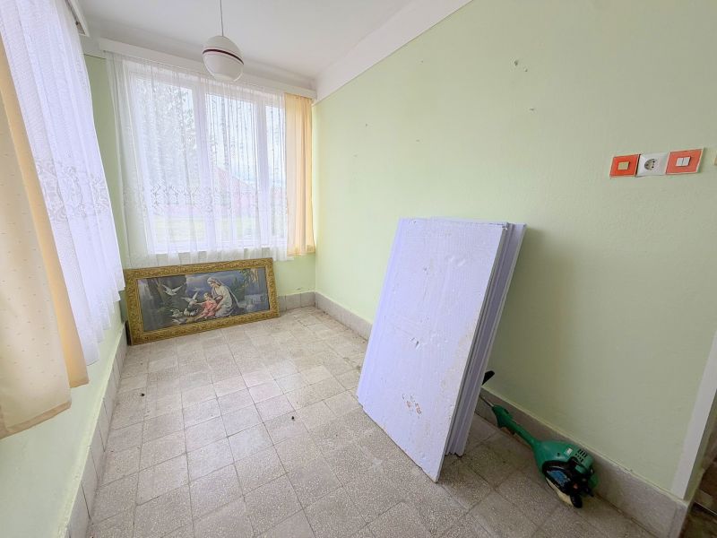 Das Innere eines Einfamilienhauses mit einem Bild, Fenstern mit weißen Vorhängen und grünen Wänden.