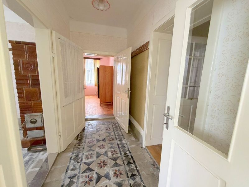 Flur mit Kachelofen und Fliesen in einem Einfamilienhaus.