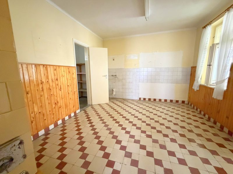 Küche in einem Einfamilienhaus mit Fliesenboden und Holzverkleidung an den Wänden.