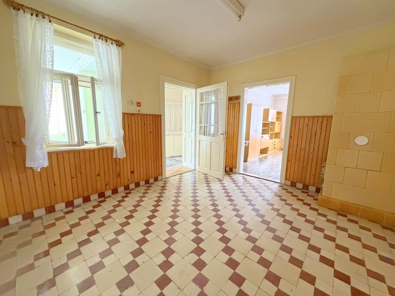 Innenraum eines Einfamilienhauses, heller Raum mit Fliesenboden und Holzverkleidung an den Wänden.