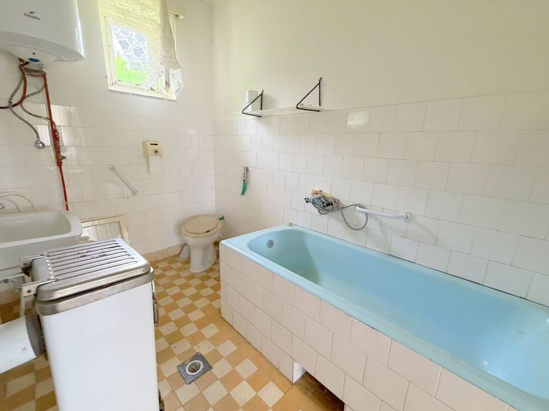 Badezimmer mit Badewanne und Fliesen in einem Einfamilienhaus mit einfacher Ausstattung.