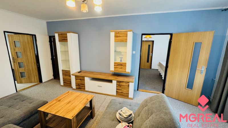 Wohnzimmer in einer 3-Zimmer-Wohnung mit grauen Wänden und Holzmöbeldekor.