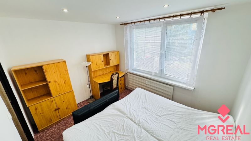 Schlafzimmer in einer 3-Zimmer-Wohnung mit Holzmöbeln und großem Fenster.