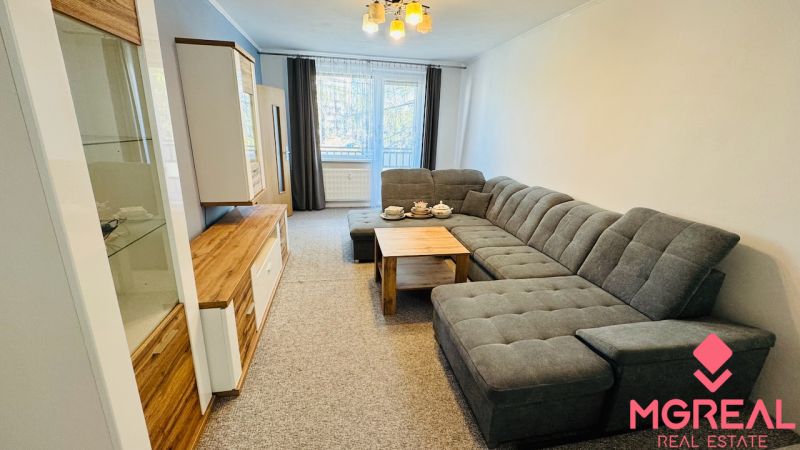 Wohnzimmer in einer 3-Zimmer-Wohnung mit einem bequemen Sofa und einem Boden in Holzoptik.