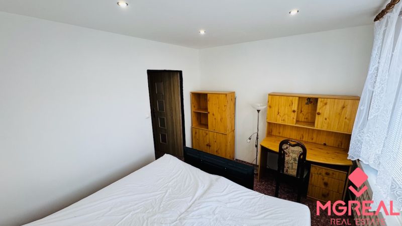 Ein Zimmer mit einem Schreibtisch und Holzmöbeln in einer 3-Zimmer-Wohnung.