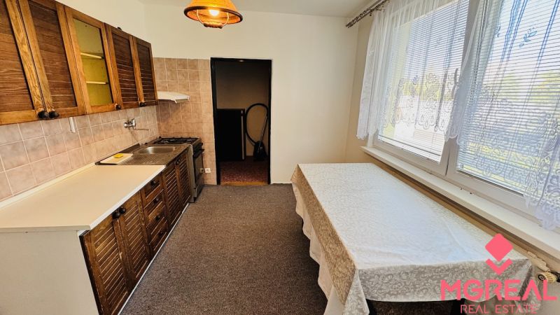 Küche in einer 3-Zimmer-Wohnung mit hellen Wänden, Holzschränken und Esstisch.