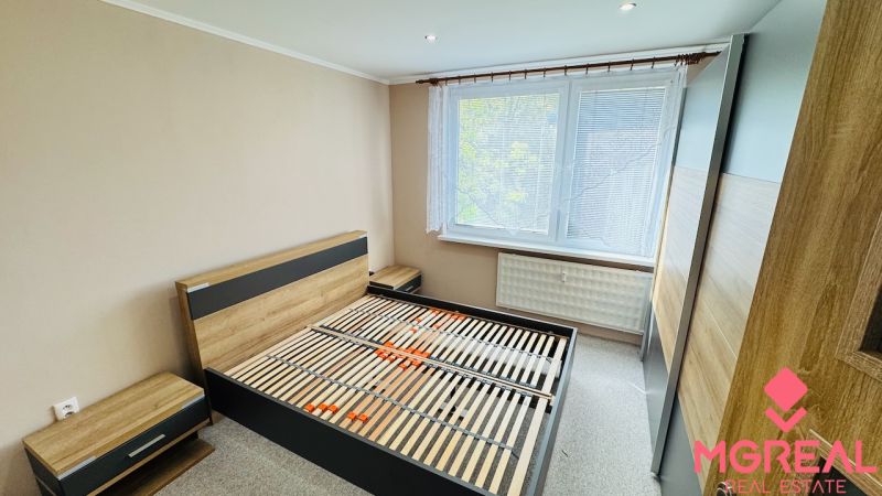Schlafzimmer mit Bett, Nachttischen und großem Kleiderschrank in einer 3-Zimmer-Wohnung.
