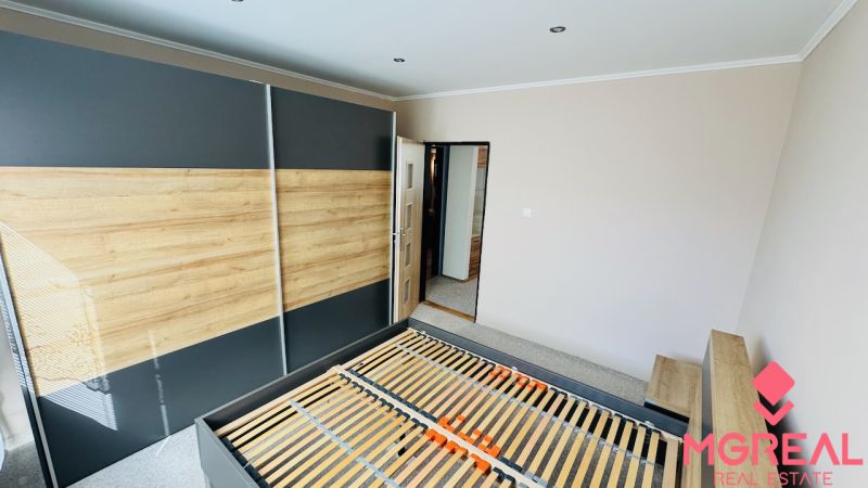 Schlafzimmer mit Einbauschrank und Bett in einer 3-Zimmer-Wohnung mit Holzboden.