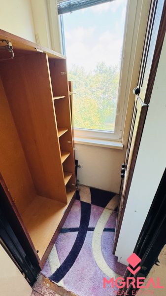 Ein Kleiderschrank in einer 3-Zimmer-Wohnung mit Blick durch ein großes Fenster und einem bunten Teppich.