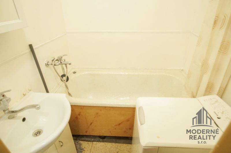 Badezimmer in einer 2-Zimmer-Wohnung mit Badewanne, Waschbecken und Waschmaschine.