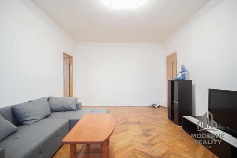 Wohnzimmer mit grauem Sofa und Holzboden in einer 2-Zimmer-Wohnung.