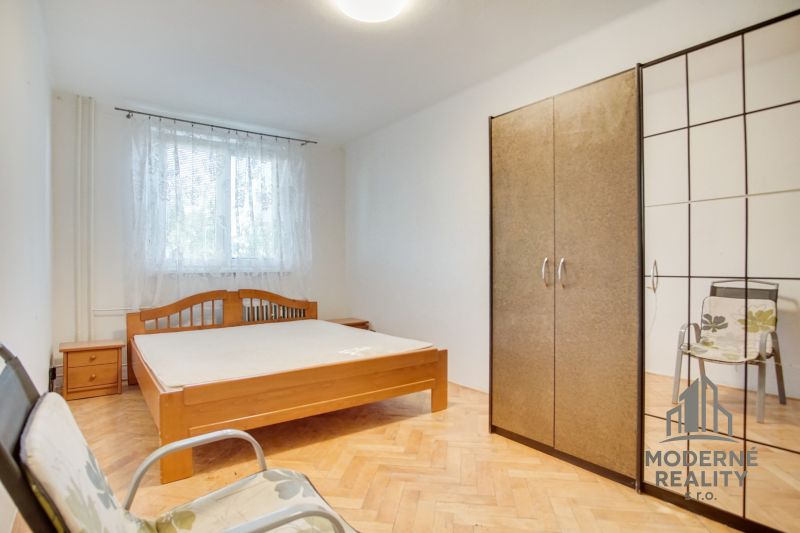 Schlafzimmer in einer Zweizimmerwohnung mit Holzboden, Bett und Schrank.