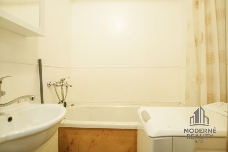 Badezimmer in einer 2-Zimmer-Wohnung mit Waschbecken, Badewanne und Waschmaschine.