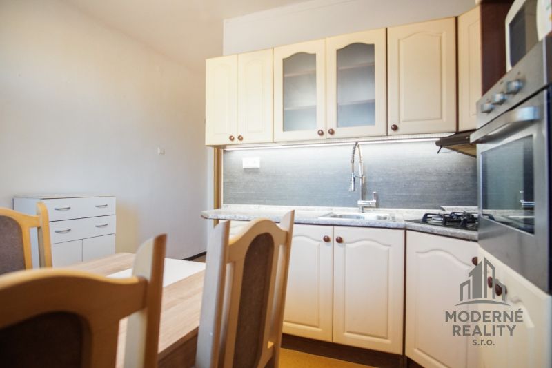 Küchenzeile in einer 2-Zimmer-Wohnung mit Holzdekor und eingebautem Backofen.