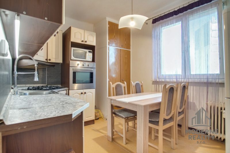 Küche einer 2-Zimmer-Wohnung mit Esstisch, Küchenzeile und großem Fenster.