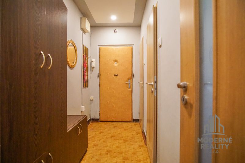 Ein enger Flur in einer 2-Zimmer-Wohnung mit einem Boden in Holzoptik und Holzmöbeln.