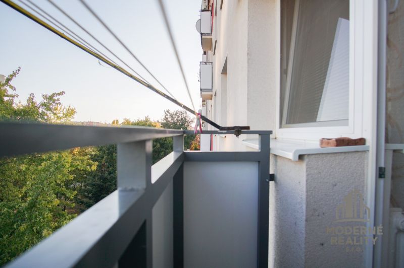 Balkon einer 2-Zimmer-Wohnung in Nové Zámky mit Blick auf grüne Bäume.