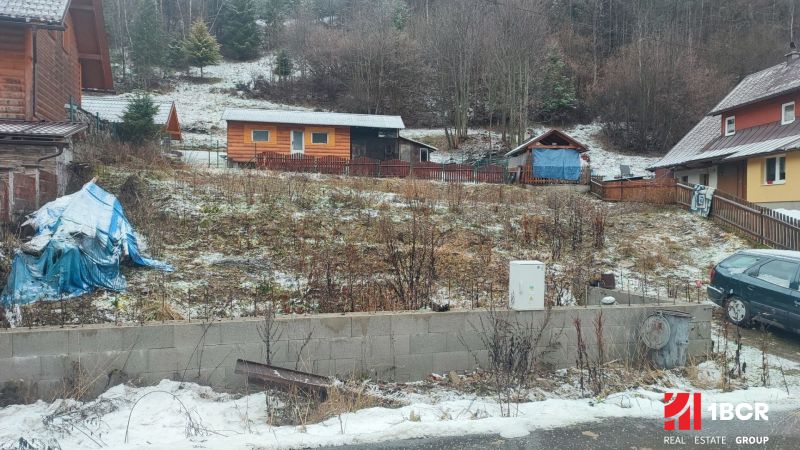 Ein verschneites Grundstück mit einem Einfamilienhaus in Oščadnica, umgeben von Grünflächen und Holzstrukturen.