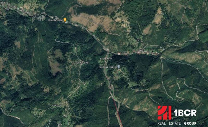 Luftaufnahme von Oščadnica mit umliegenden bewaldeten Gebieten, Straßen und Gebäuden.