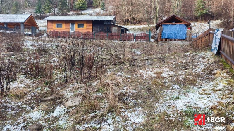 Holzhütten am verschneiten Hang in Oščadnica bei einem Einfamilienhaus.