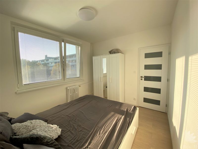 Schlafzimmer in einer 3-Zimmer-Wohnung mit Bett, Schrank, Fenster und modernen Türen.