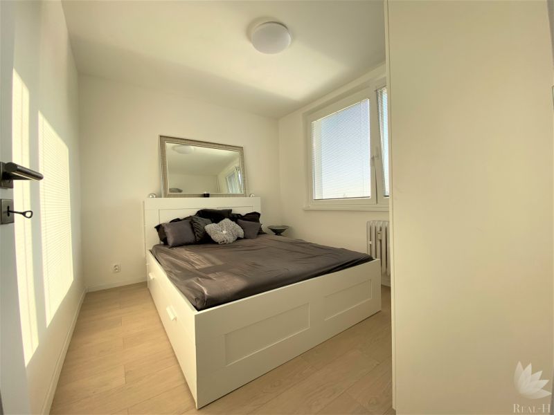 Schlafzimmer mit großem Bett, Spiegel und Fenstern in einer 3-Zimmer-Wohnung.