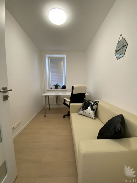 Ein enger Arbeitsbereich in einer 3-Zimmer-Wohnung mit einem Tisch, einem Stuhl und einem Sofa.