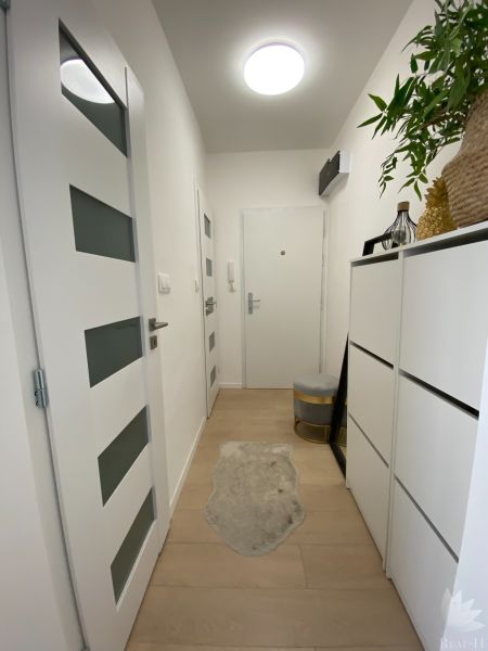 Der Flur einer 3-Zimmer-Wohnung mit weißen Möbeln und Holzboden.