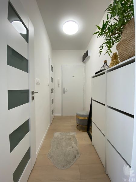 Ein Flur mit weißen Wänden und Möbeln in einer 3-Zimmer-Wohnung, dekoriert mit Pflanzen.