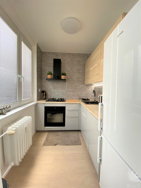 Küche in einer 3-Zimmer-Wohnung mit weißen Schränken, einem Gasherd und einem Heizkörper.
