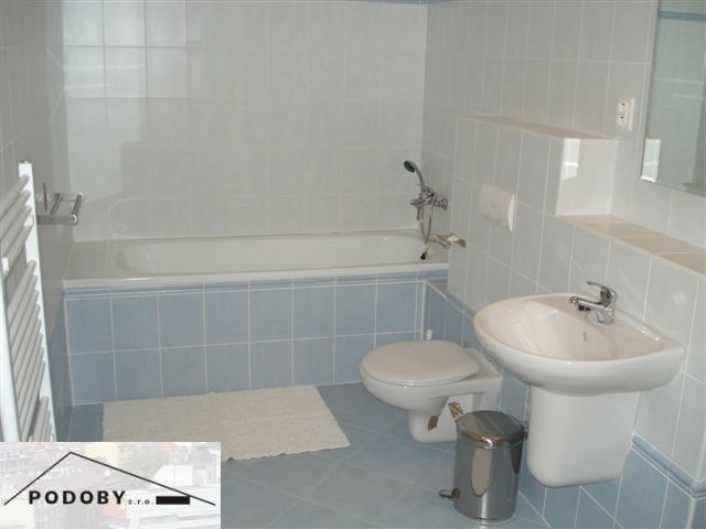 Badezimmer in einer 3-Zimmer-Wohnung mit Badewanne, Waschbecken und Toilette, blau-weiße Fliesen.