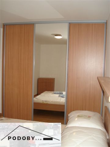 Schlafzimmer in einer 3-Zimmer-Wohnung mit einem großen Einbauschrank und einem Boden mit Holzdekor.