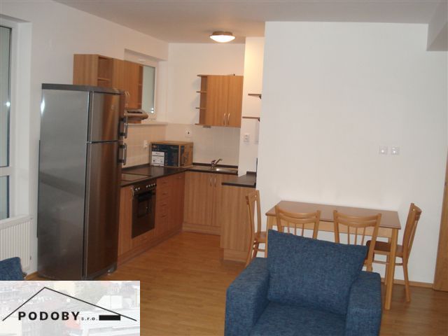 Küche in einer 3-Zimmer-Wohnung mit Küchenzeile, Esstisch und Boden mit Holzdekor.