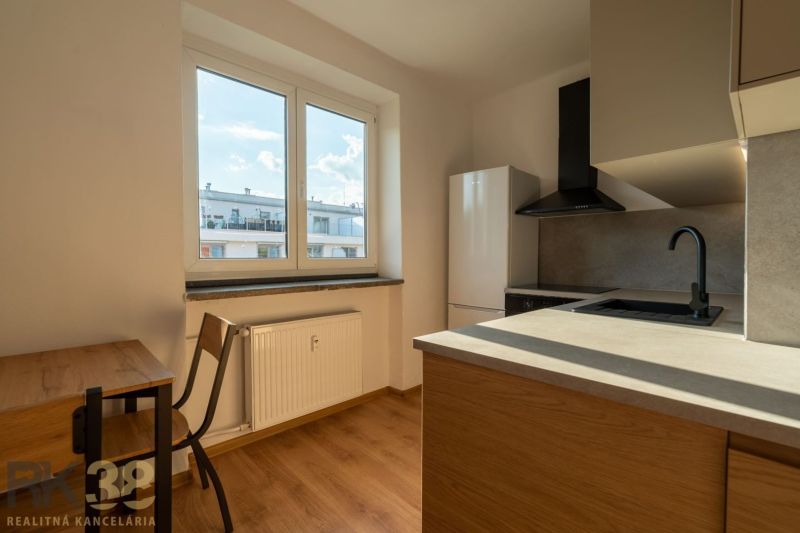 Küche in einer Einzimmerwohnung mit Holzboden und Blick aus dem Fenster.