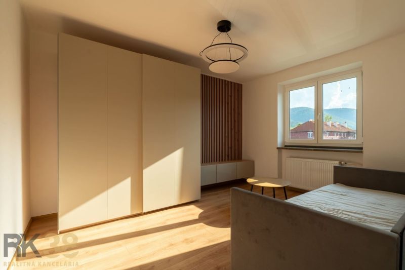 Ein Zimmer in einer Einzimmerwohnung mit einem Boden in Holzoptik, einem Sofa und einem Kleiderschrank.