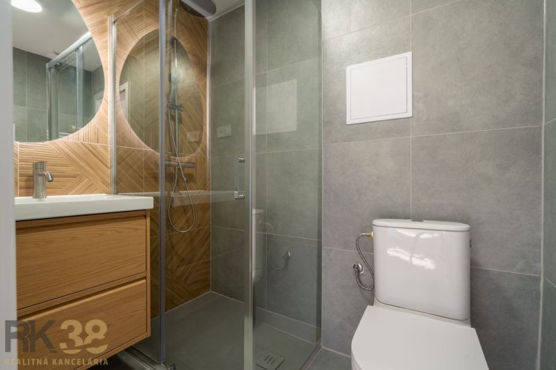 Badezimmer mit Dusche, Waschbecken und Toilette in einer Einzimmerwohnung.