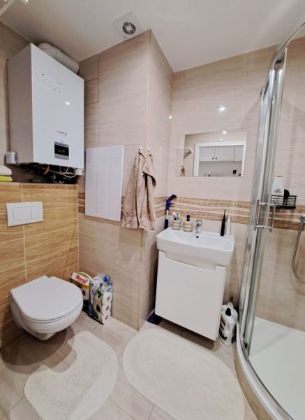 Badezimmer in einer 3-Zimmer-Wohnung mit Toilette und Duschkabine, helle Fliesen.